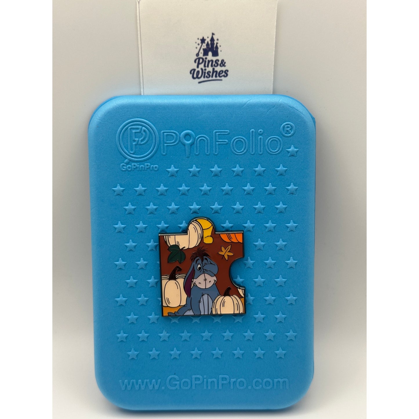 Loungefly Disney Winnie the Pooh Autumn Puzzle Blind Box Enamel Pin - Eeyore on a blue Background pin board with the Pins and Wishes Logo